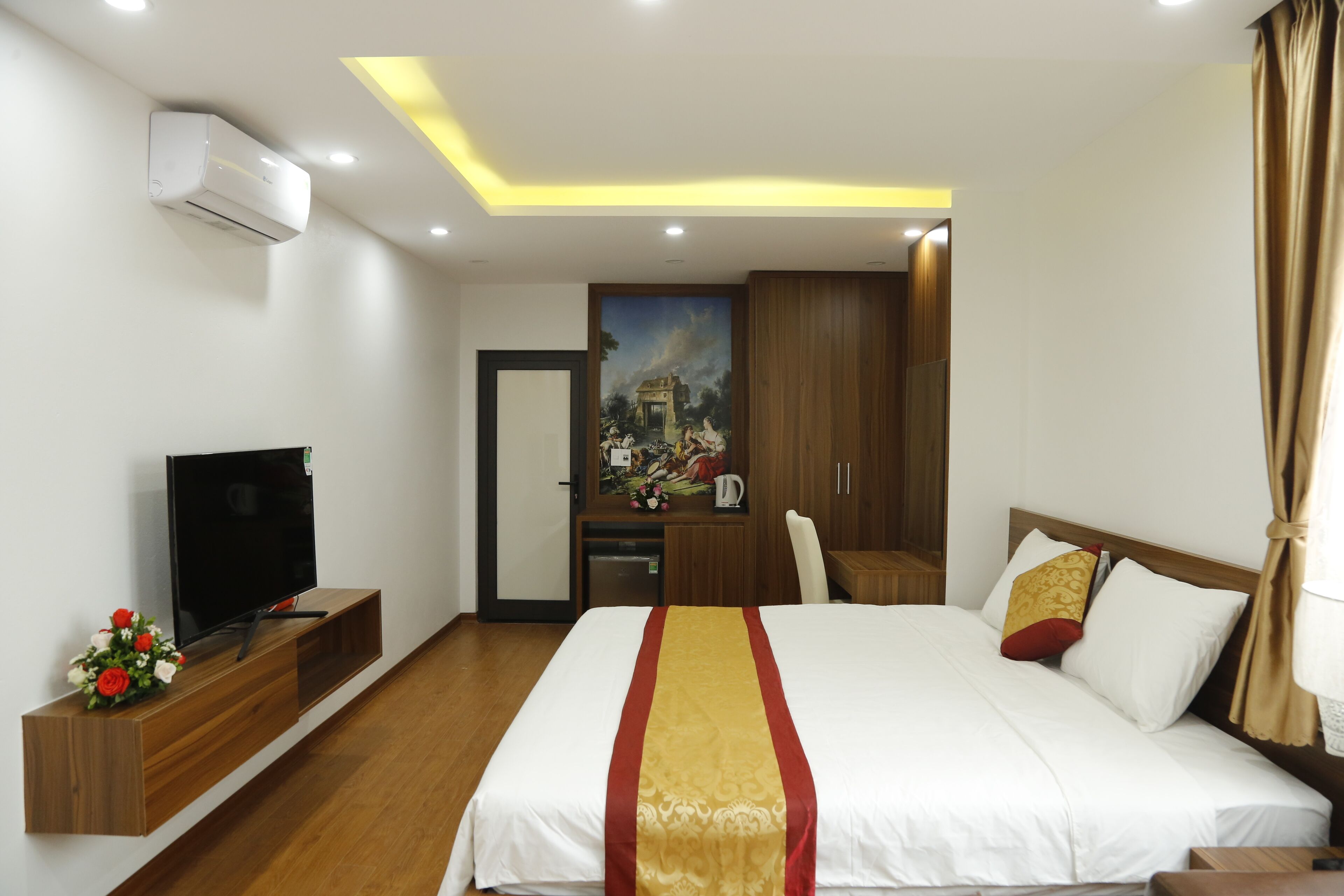 Habitación de hotel con una cama grande, un televisor de pantalla plana, un escritorio de madera y un cuadro en la pared.
