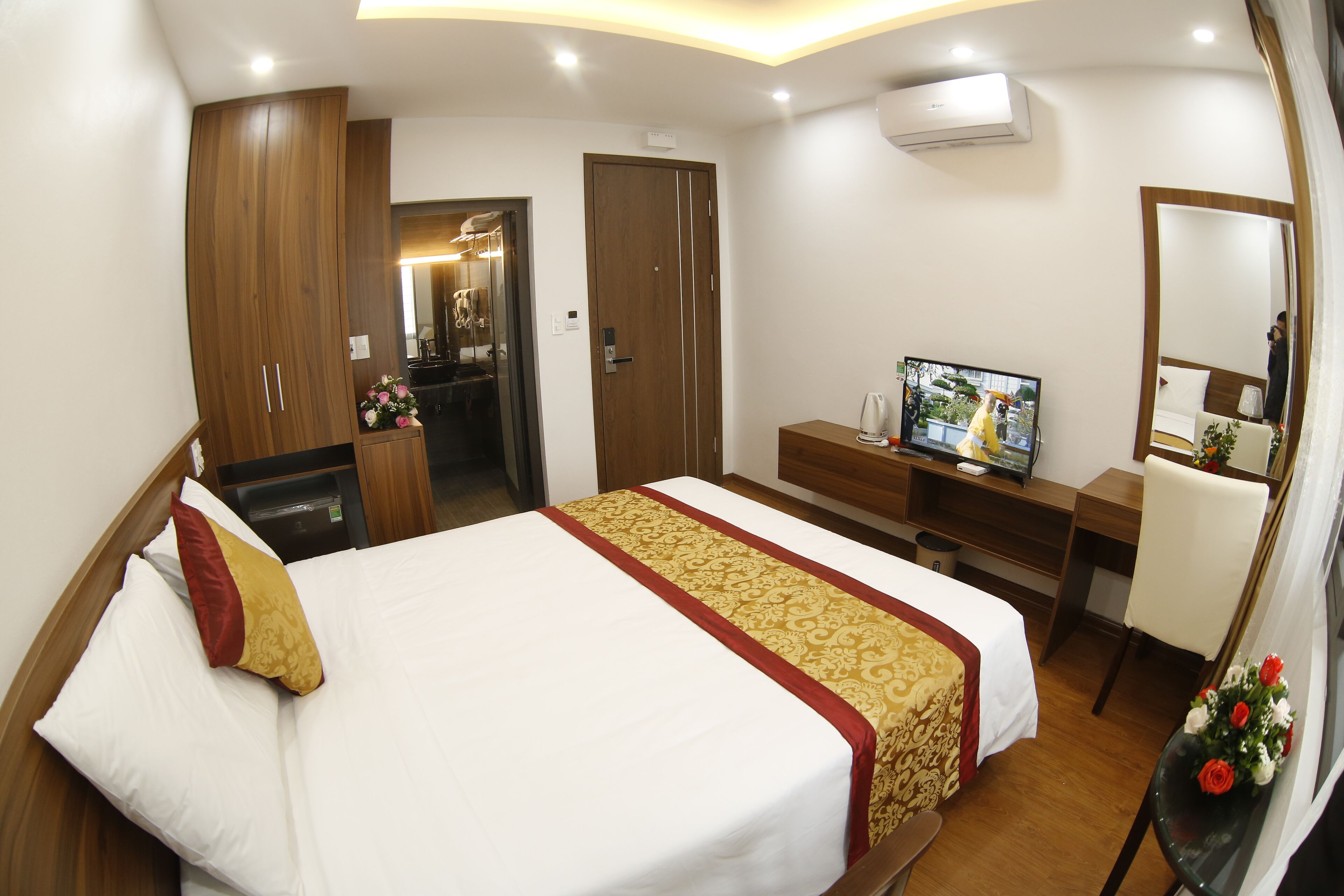 A hotel room with a bed, a desk, a television, and a mirror.