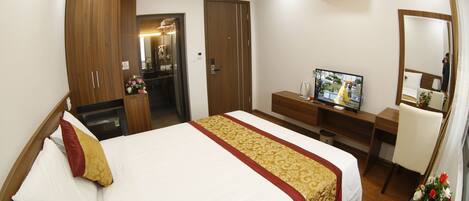 A hotel room with a bed, a desk, a television, and a mirror.