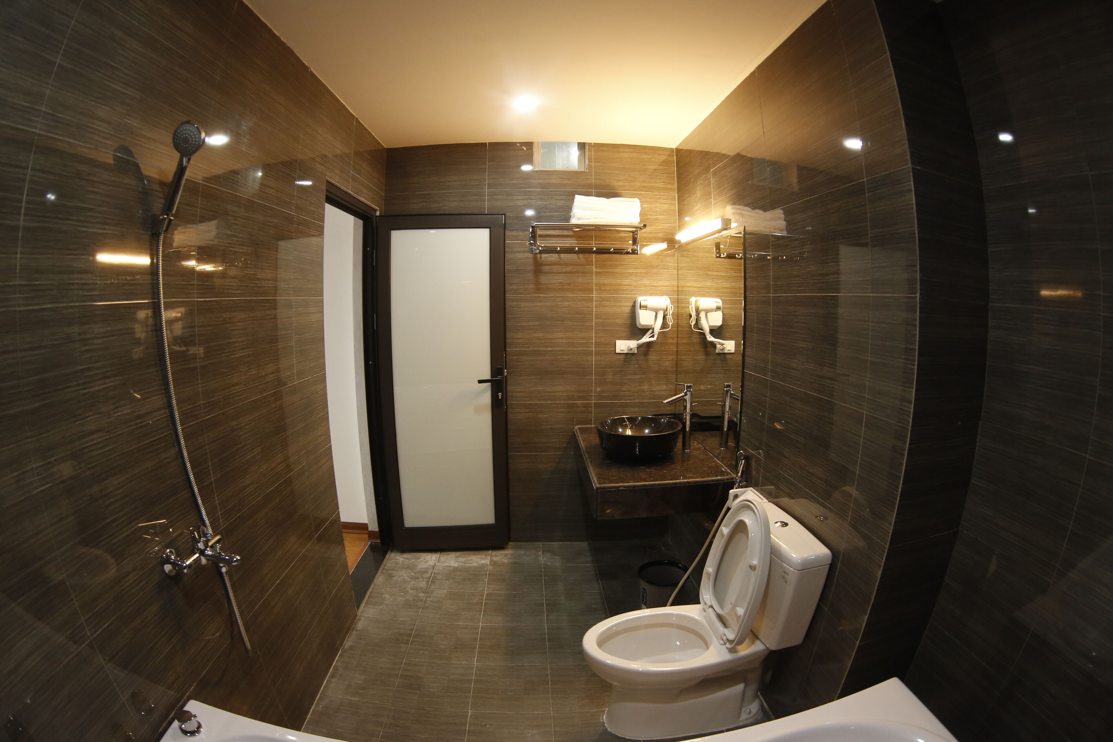 Een moderne badkamer met douche, toilet, wastafel en handdoekhouder.