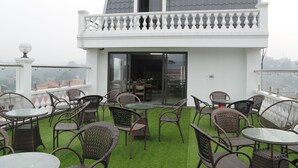 Une terrasse sur le toit, aménagée avec des meubles en osier et une table en verre, offrant une vue sur le paysage urbain.