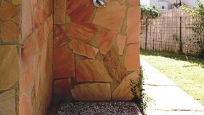 A stone shower enclosure with a built-in water feature, a small step leading into the shower, and a satellite dish on the roof. - Costa Rei Centro three-room apartment (Costa Rei)