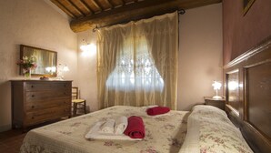 A bedroom with a bed, a dresser, a mirror, and a window with curtains. - Typical, Charming With Chianti View (Bucine)