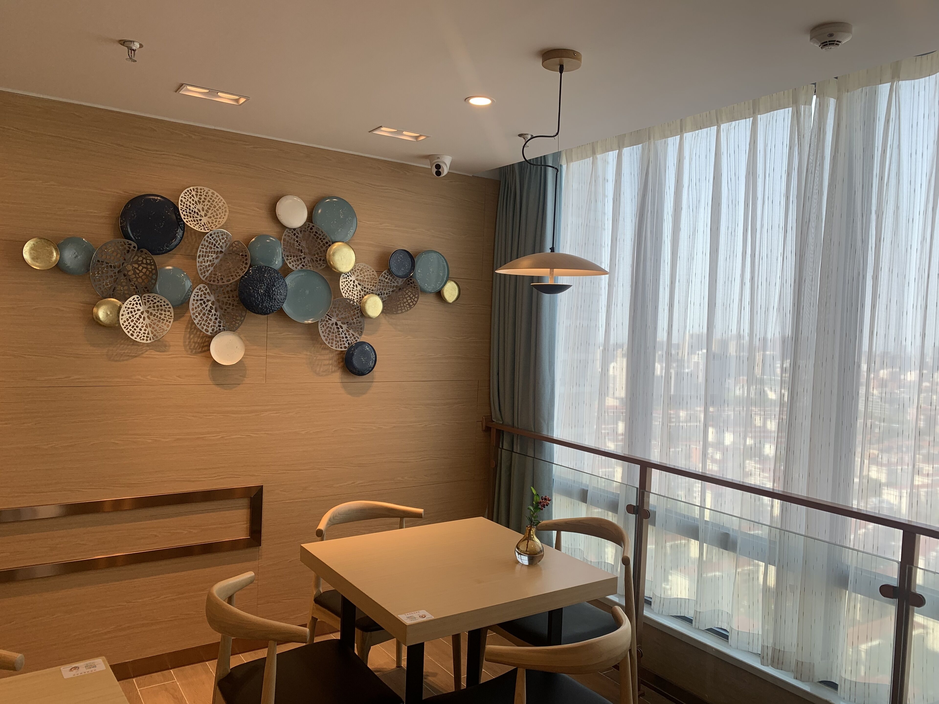 A modern dining area with a wooden wall, a glass railing, and a table with chairs.