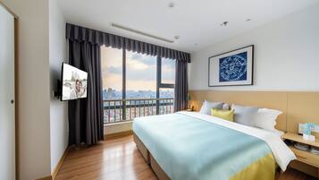Una camera d'albergo con un letto grande, vista sulla città, una TV a schermo piatto e un quadro appeso al muro.