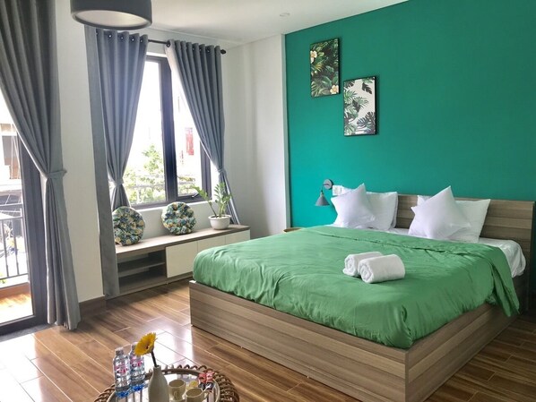 A bedroom with a green bedspread, wooden headboard, and a window with curtains. - Kivi Homestay (Da Nang)