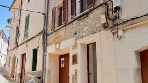 Une rue étroite bordée d’immeubles aux façades en pierre, aux volets en bois, et devant laquelle est garé un vélo.