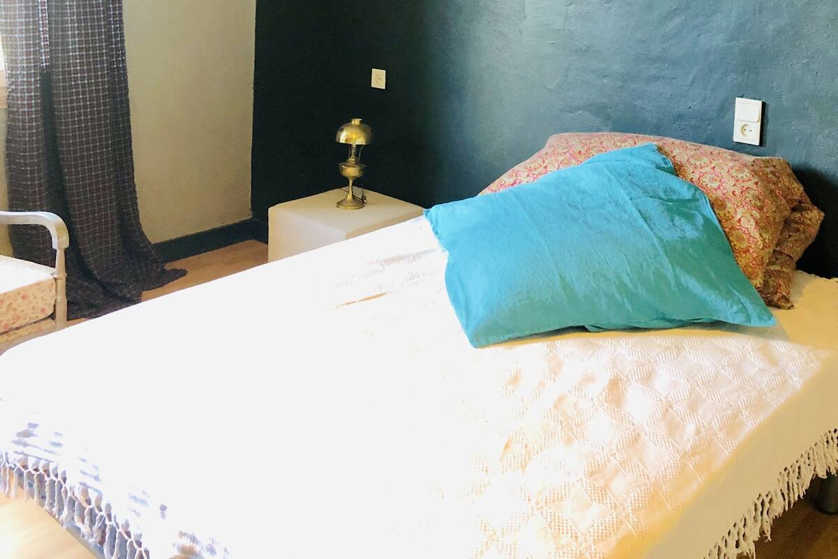 Een slaapkamer met een bed, een nachtkastje, een lamp en een wandlamp.