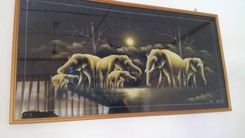 A framed artwork depicting elephants by a water body under a night sky with a full moon.