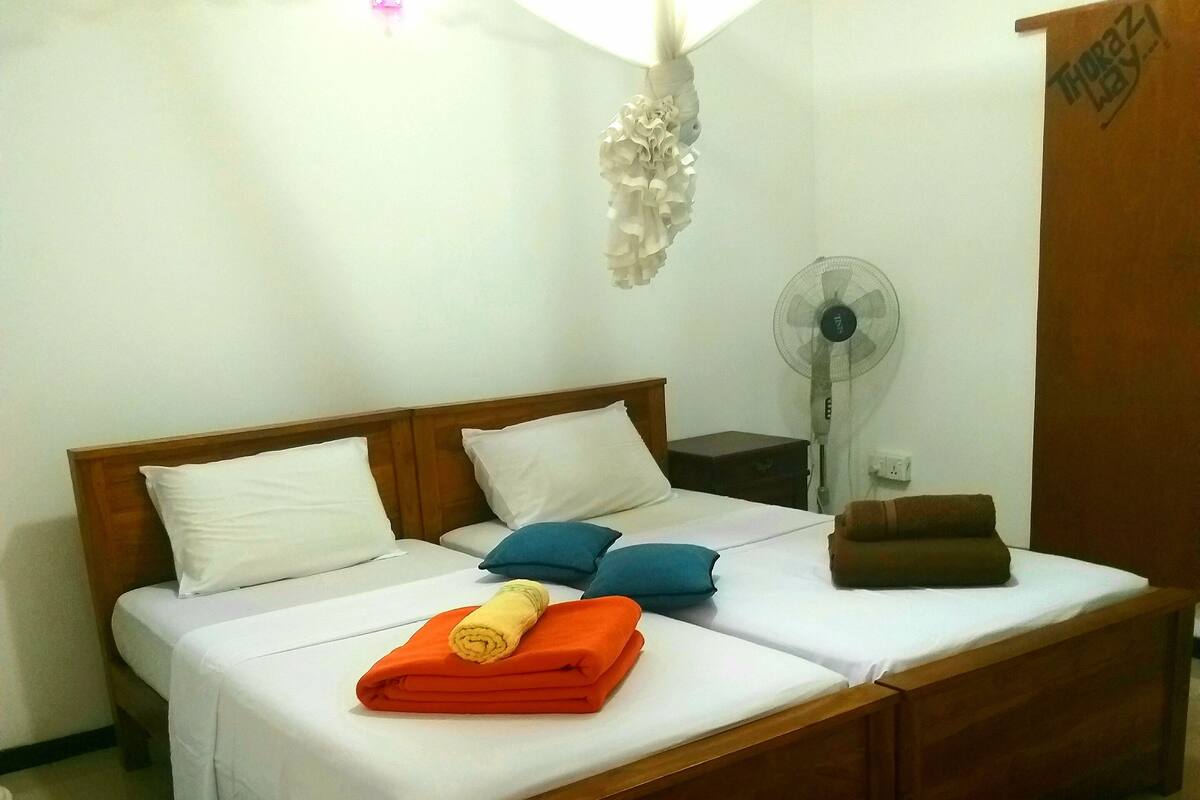 A double bed with white and blue pillows, a wooden headboard, and a small wooden chest.