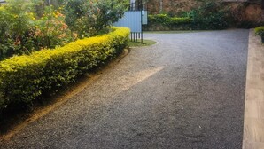 A gravel driveway leading to a building with a metal fence and lush greenery. - 59B Rest Inn Ella (Ella)