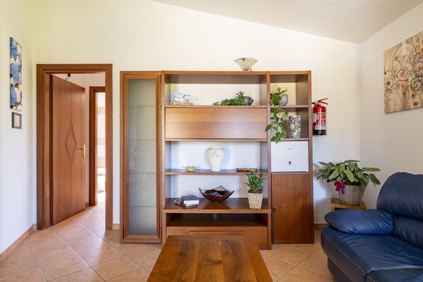 A living room with a wooden cabinet, a blue sofa, and a coffee table.