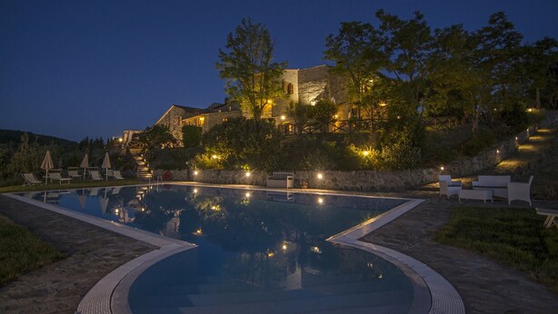 A swimming pool with lounge chairs and a stone building in the background. - La Scaletta Della Rocca (Castellina in Chianti)