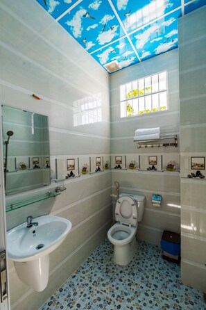 A bathroom with a toilet, sink, and shower. There is a window with a view of greenery outside. - Hotel Huong Dao (Ho Chi Minh City)