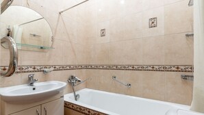 A bathroom with a sink, mirror, bathtub, and decorative tiles. - RentWill Sadovo-Spasskaya 244 (Sadovo)