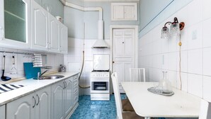 A compact kitchen with white cabinets, a stove, and a dining table. - RentWill Sadovo-Spasskaya 244 (Sadovo)