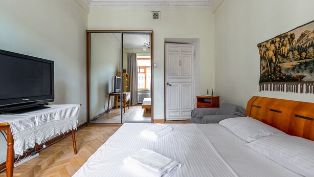 A hotel room with a bed, a television on a table, a painting on the wall, and a door leading to another room. - RentWill Sadovo-Spasskaya 244 (Sadovo)