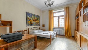 A room with a bed, a desk with a typewriter, a large painting, a window with curtains, and wooden furniture. - RentWill Sadovo-Spasskaya 244 (Sadovo)
