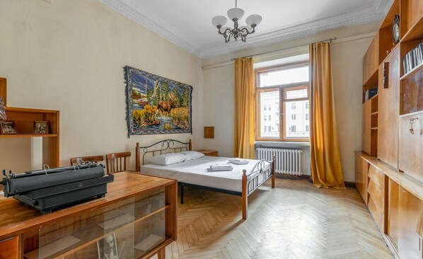 A room with a bed, a desk with a typewriter, a large painting, a window with curtains, and wooden furniture. - RentWill Sadovo-Spasskaya 244 (Sadovo)