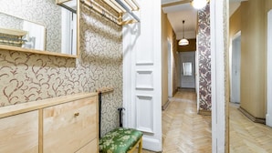 A hallway with patterned wallpaper, a wooden bench with a green cushion, and a hanging rack. - RentWill Sadovo-Spasskaya 244 (Sadovo)