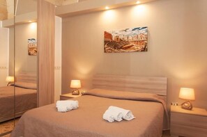 A hotel room with a large bed, two bedside tables with lamps, a mirror, and a painting on the wall. - Wish Rooms (Lecce)