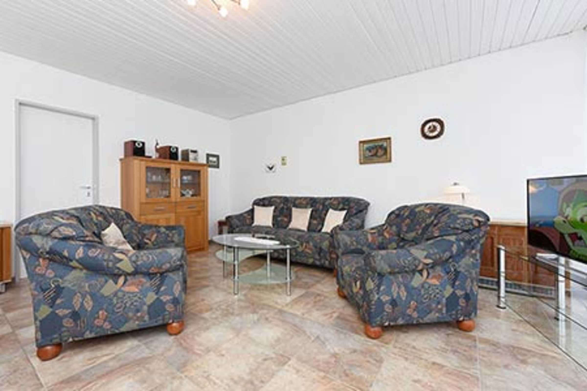 Una sala de estar con dos sofás estampados, una mesa de centro y un aparador.