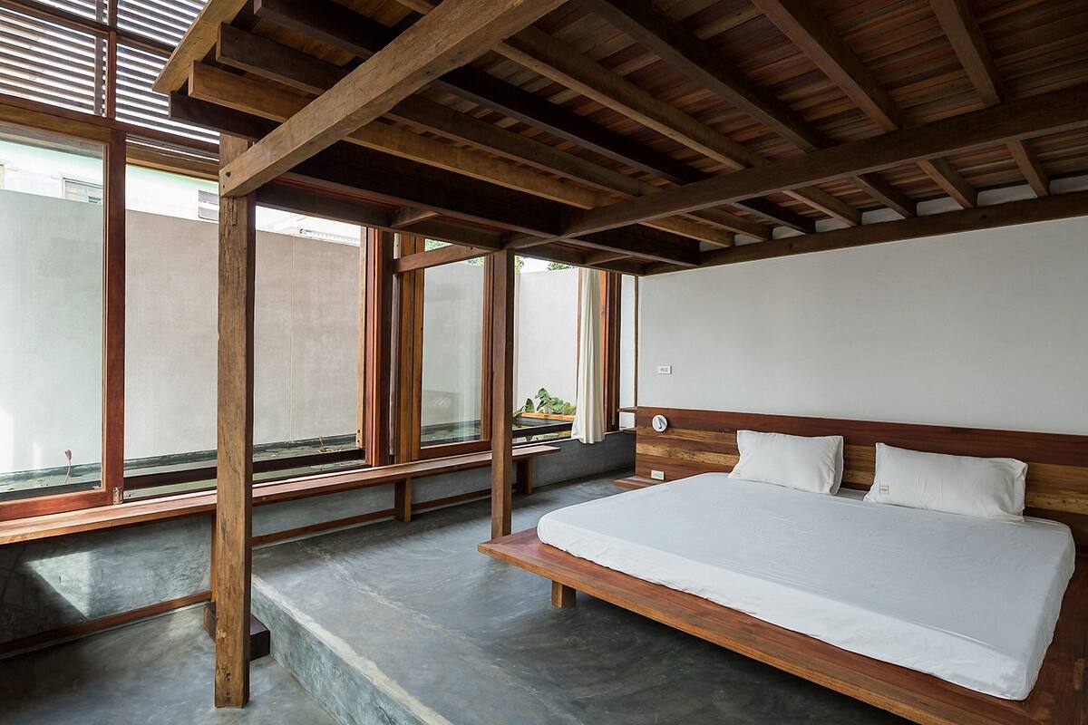 Un dormitorio con estructura de cama de madera, un ventanal y vista al exterior.