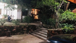 Vista noturna de um edifício com uma escadaria de pedra que leva a uma entrada iluminada.