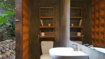 Ein Badezimmer mit Toilette, Waschbecken und Ablagen mit Pflegeprodukten.