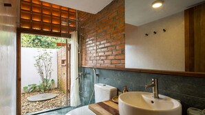 Um banheiro moderno com uma pia grande, vaso sanitário e área de chuveiro.