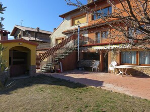 Ein zweistöckiges Gebäude mit Sandsteinfassade, einer Holztreppe und einer Terrasse mit Sitzgelegenheiten.
