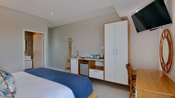 Une chambre à coucher comprenant un lit, un bureau, une chaise, un téléviseur et une armoire.