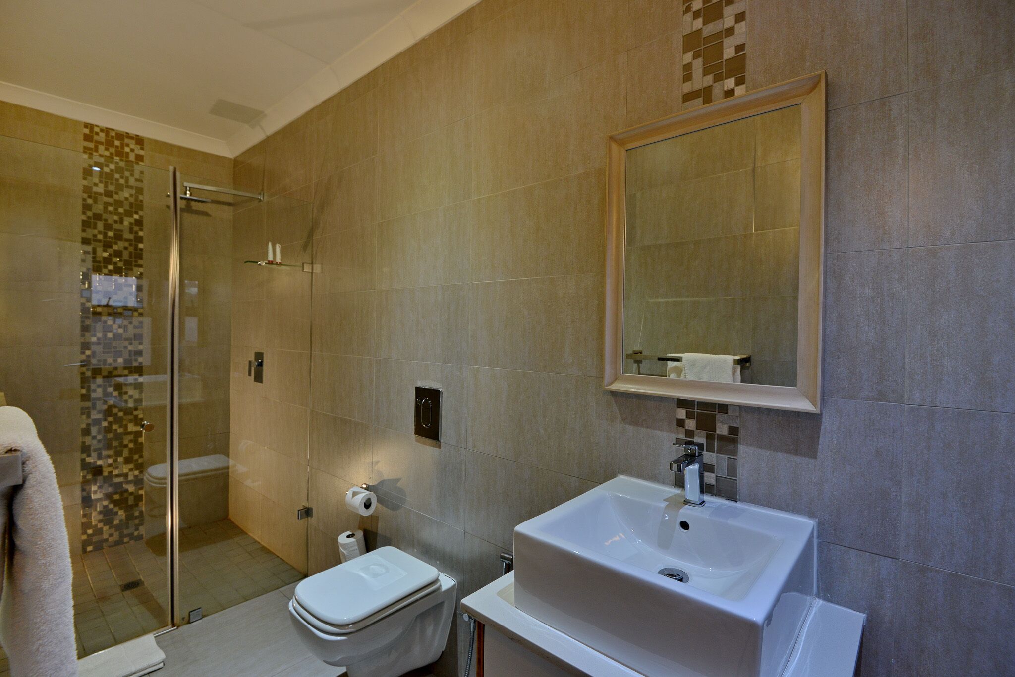 A modern bathroom with a glass-enclosed shower, a white sink, and a large mirror.