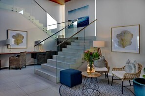 Un interior moderno con una escalera, una zona de estar y obras de arte.