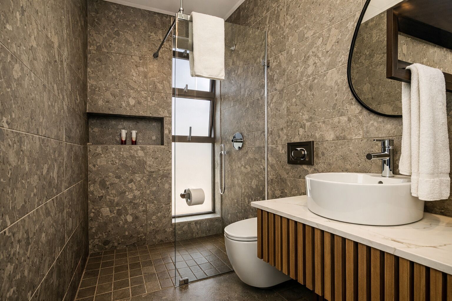A modern bathroom with a glass shower enclosure, a white sink, and a toilet.