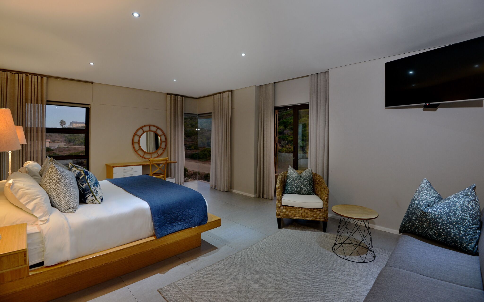 Una habitación de hotel moderna con una cama grande, un escritorio, una silla, un sofá y un televisor.