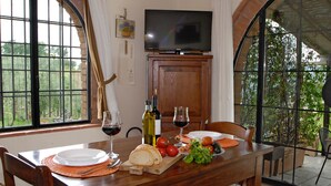 Une table à manger dressée avec des assiettes, du pain, des tomates et des verres à vin.