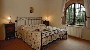 Une chambre à coucher avec un lit, deux tables de chevet, une fenêtre et un radiateur.