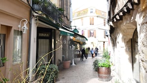 A narrow street with buildings on both sides, potted plants, and a few pedestrians. - Charming studio "Le Colombier" - Habitation Saint-Clar Historic Center - WIFI / Netflix (Bergerac)