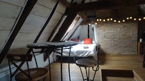 A cozy attic bedroom with a bed, a small table, and two stools. - Charming studio "Le Colombier" - Habitation Saint-Clar Historic Center - WIFI / Netflix (Bergerac)