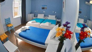 Habitación de hotel con una cama curvada, una mesita, una silla, una ventana con cortinas y un espejo.