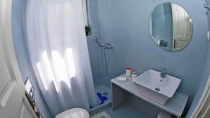 Un baño con ducha, inodoro, lavamanos y un espejo en la pared.