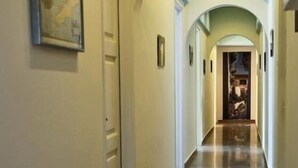 Un pasillo con piso pulido, paredes blancas y techo abovedado.