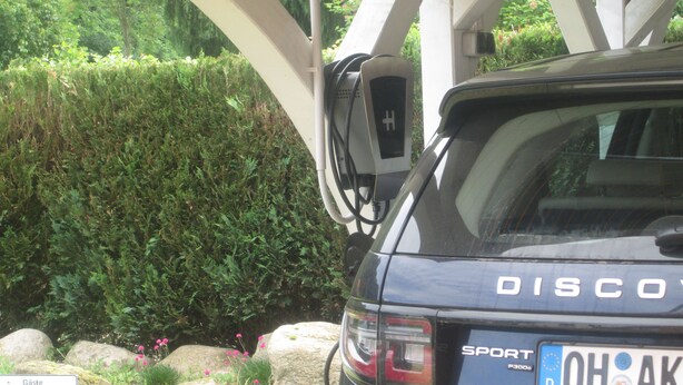 A car parked under a white structure with a license plate reading "OH AK". - Apartments with a large balcony near the beach (Bosau)