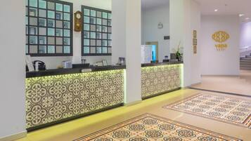 Un hall d'hôtel avec un sol à motifs, un comptoir d'accueil et une enseigne placée au-dessus.