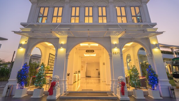 A grand entrance with a central archway, flanked by two smaller arches, leading to a well-lit interior. - Vapa Hotel (Phuket)