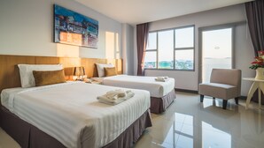 A hotel room with two beds, a desk, a chair, and a large window offering a city view. - Vapa Hotel (Phuket)