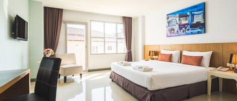 A hotel room with a bed, a desk, a chair, a TV, and a painting on the wall.