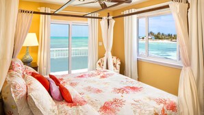 A bedroom with a bed, curtains, a window, and a view of the ocean. - LUXURY HOUSE WITH PRIVATE BEACH (Nassau)
