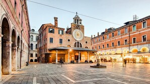 A historic square with a prominent clock tower, a covered entrance, and traditional architecture. - San Marco Design Suites (Venice)